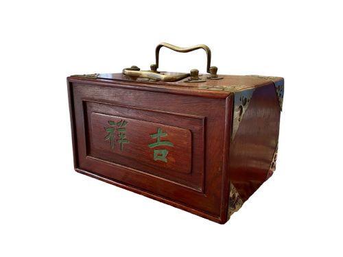 fig 1. A dark brown wooden Chinese mahjong box featuring brass corner brackets, a top handle, and green Chinese characters painted on the front panel.