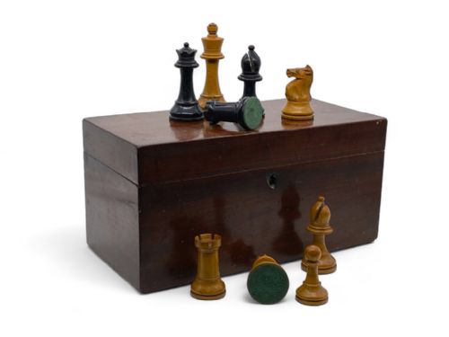 fig 1. An open rectangular mahogany storage box lined with green felt, containing turned natural boxwood and ebonised Staunton chess pieces.