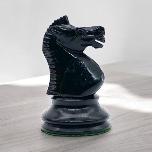 fig 2. A boxwood and ebony Staunton chess set featuring carved chessmen displayed in and around an open mahogany wooden storage box lined with green felt.