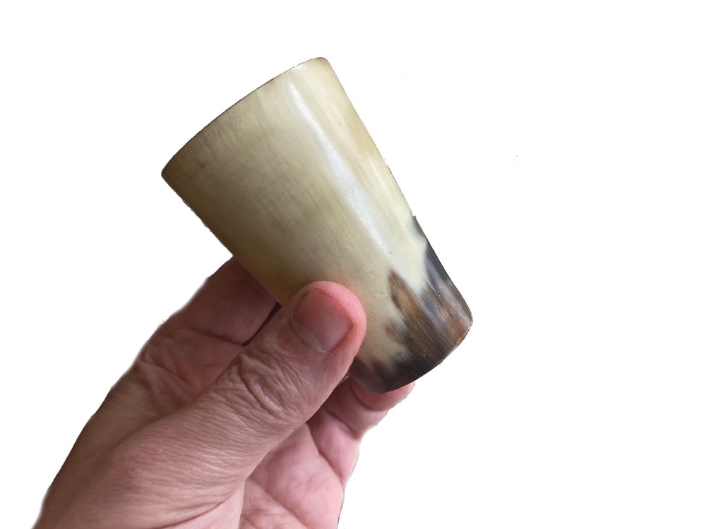 A small translucent honey-coloured antique horn beaker inscribed with the word Grindelwald around the upper rim. View II