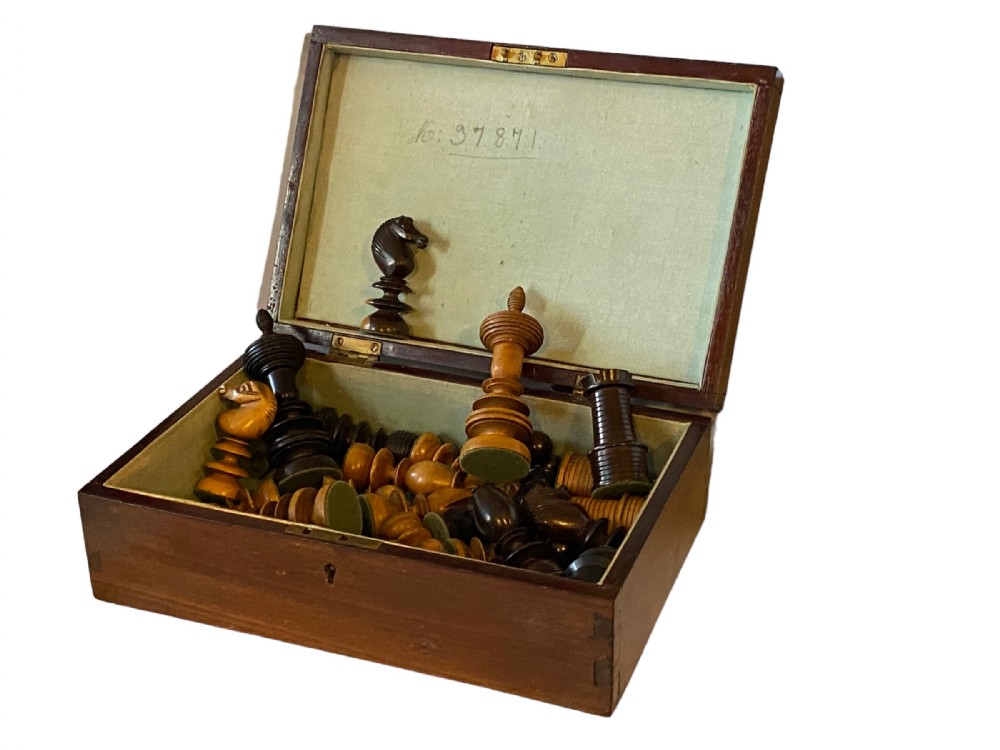 A 19th-century English chess set with turned rosewood and boxwood pieces contained within an open hinged wooden presentation box lined with pale green cloth.