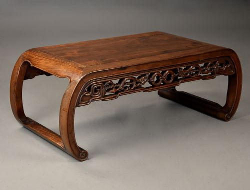 fig 1. An early 20th-century rectangular Chinese low table crafted from warm brown padouk wood, featuring a carved openwork apron and rounded legs with scroll feet.