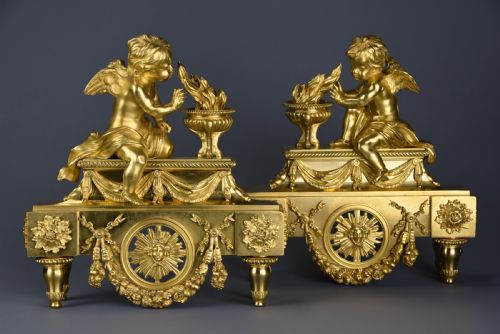 fig 2. A pair of late nineteenth-century gilded bronze fire dogs featuring seated winged cherubs warming their hands by flaming urns above solar masks and drapery.