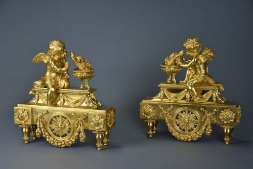 fig 3. A pair of late nineteenth-century gilded bronze fire dogs featuring seated winged cherubs warming their hands by flaming urns above solar masks and drapery.