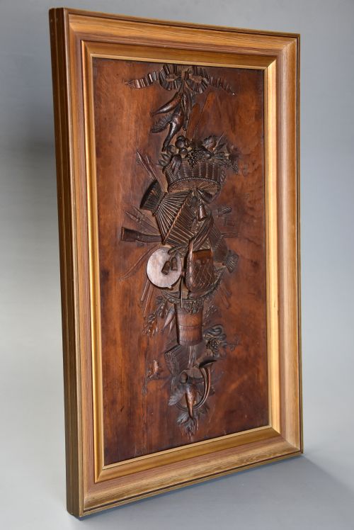 fig 1. A framed mid-19th-century Continental fruitwood panel featuring a high-relief carved vertical trophy motif of hunting equipment, fruit, and foliage.