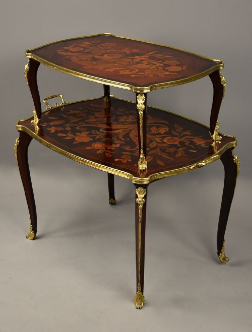 fig 1. A two-tiered French style dark wood etagere featuring elaborate floral marquetry inlays, curved cabriole legs, and ornate gilt-bronze mounts along the rims and feet.