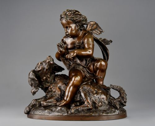 fig 1. A late 19th-century dark patinated bronze sculpture depicting a winged putto interacting with a recumbent spaniel dog on an oval base.