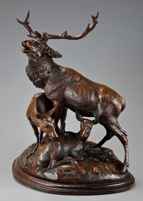 fig 1. A late 19th-century dark carved linden wood sculpture depicting a roaring stag standing above a doe and lying fawn on a naturalistic base.