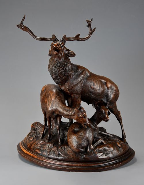 fig 2. A late 19th-century dark carved linden wood sculpture depicting a roaring stag standing above a doe and lying fawn on a naturalistic base.