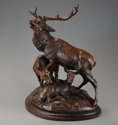 fig 3. A late 19th-century dark carved linden wood sculpture depicting a roaring stag standing above a doe and lying fawn on a naturalistic base.