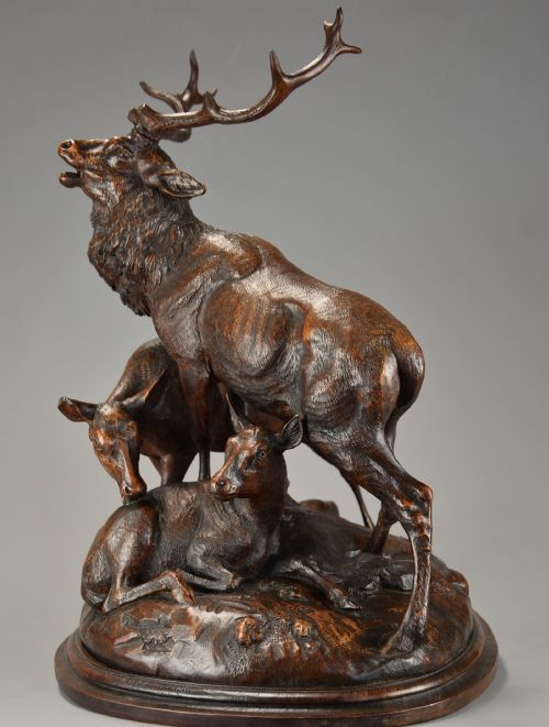 fig 4. A late 19th-century dark carved linden wood sculpture depicting a roaring stag standing above a doe and lying fawn on a naturalistic base.