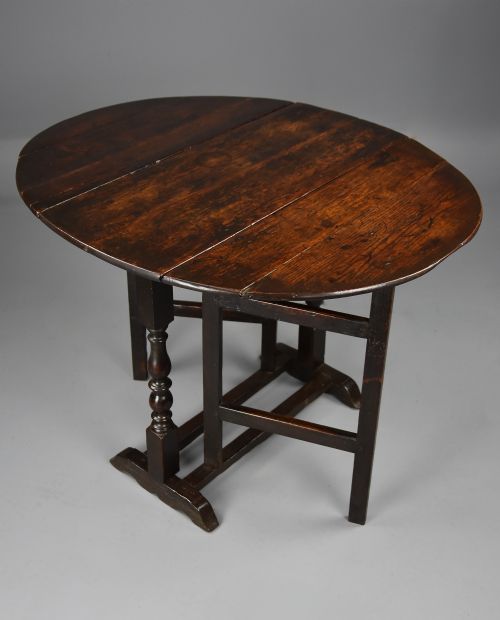 fig 1. A seventeenth-century dark oak gateleg table shown with both drop-down leaves extended to form an oval tabletop supported on turned legs.