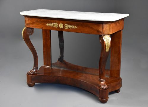 fig 1. An early nineteenth-century French Charles X mahogany console table with a white marble top, curved front legs ending in paw feet, gilt-bronze mounts, and a mirrored back above a concave base.