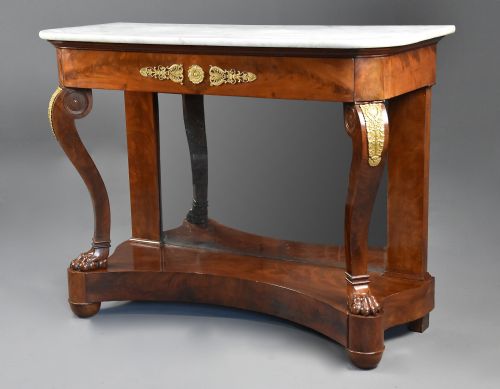 fig 2. An early nineteenth-century French Charles X mahogany console table with a white marble top, curved front legs ending in paw feet, gilt-bronze mounts, and a mirrored back above a concave base.