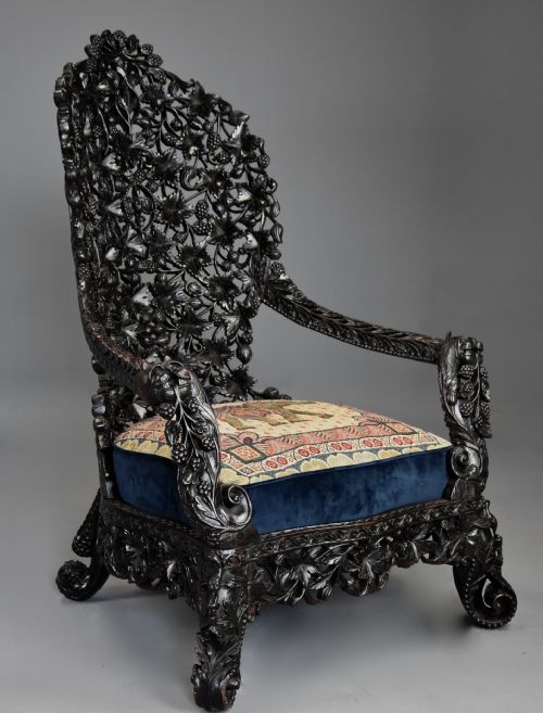 fig 1. A 19th-century Anglo-Indian carved blackwood armchair featuring an intricately pierced foliate backrest and an embroidered fabric seat cushion.