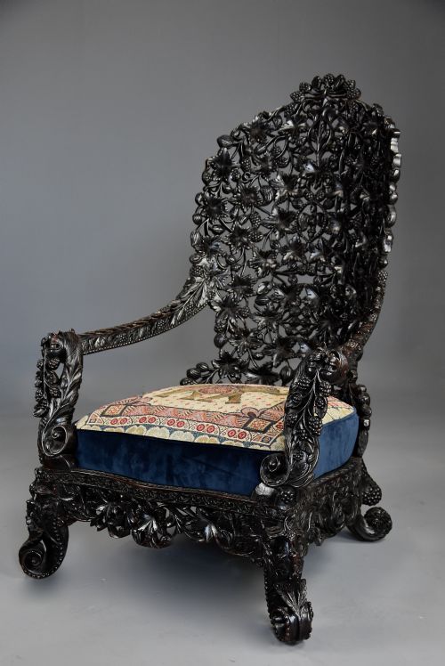 fig 2. A 19th-century Anglo-Indian carved blackwood armchair featuring an intricately pierced foliate backrest and an embroidered fabric seat cushion.