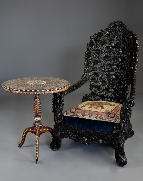 fig 3. A 19th-century Anglo-Indian carved blackwood armchair featuring an intricately pierced foliate backrest and an embroidered fabric seat cushion.