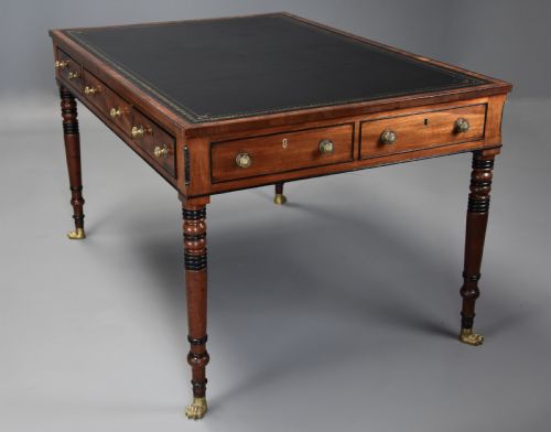 fig 2. A Regency mahogany writing table featuring a dark leather insert, six drawers with brass knobs, and reeded turned legs with brass paw feet.