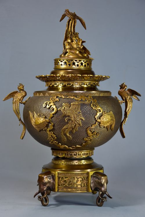 fig 1. A late nineteenth-century three-piece French Japonisme bronze garniture set featuring a central incense burner flanked by two tall urns, decorated with gilt dragon reliefs and supported on elephant head feet.