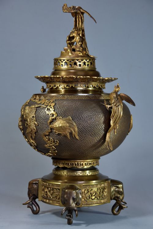 fig 3. A late nineteenth-century three-piece French Japonisme bronze garniture set featuring a central incense burner flanked by two tall urns, decorated with gilt dragon reliefs and supported on elephant head feet.
