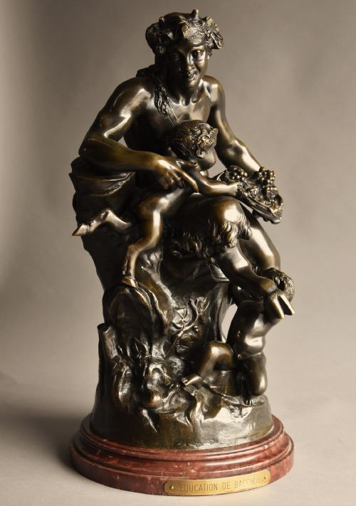 fig 2. A mid-19th century dark patinated bronze sculpture depicting a satyr seated with two young fauns, mounted on a round reddish marble base.