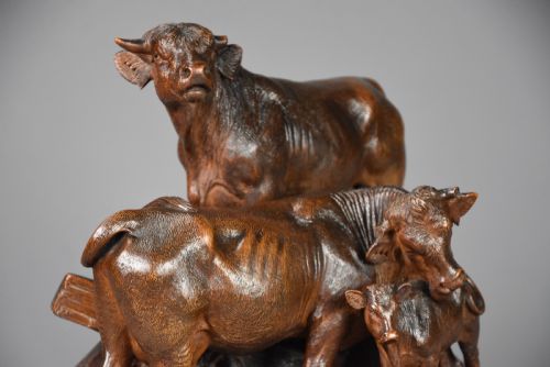fig 2. A late nineteenth-century dark linden wood sculpture depicting a bull, cow, and calf standing on a naturalistic base with carved edelweiss motifs.