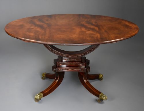 fig 2. An early nineteenth-century circular mahogany centre table shown tilted upright on a central pedestal with four splayed legs terminating in brass paw castors.