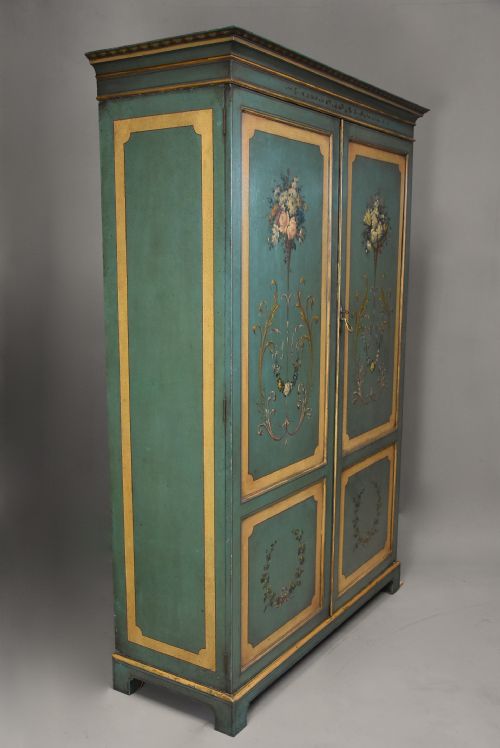 fig 3. An early twentieth-century hand-painted green and gold bedroom suite featuring a wardrobe, chest of drawers with mirror, dressing desk, side tables, and caned chairs decorated with floral urn motifs.