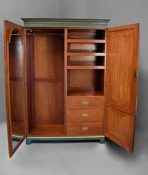 fig 4. An early twentieth-century hand-painted green and gold bedroom suite featuring a wardrobe, chest of drawers with mirror, dressing desk, side tables, and caned chairs decorated with floral urn motifs.