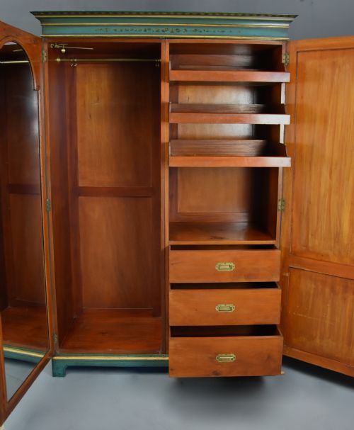 fig 5. An early twentieth-century hand-painted green and gold bedroom suite featuring a wardrobe, chest of drawers with mirror, dressing desk, side tables, and caned chairs decorated with floral urn motifs.