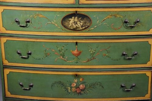 fig 9. An early twentieth-century hand-painted green and gold bedroom suite featuring a wardrobe, chest of drawers with mirror, dressing desk, side tables, and caned chairs decorated with floral urn motifs.