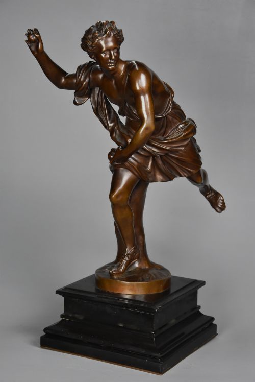 fig 1. A late 19th-century patinated bronze figure of Hippomenes in dynamic athletic posture mounted on a dark stepped plinth.