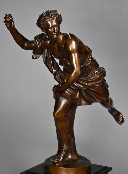fig 2. A late 19th-century patinated bronze figure of Hippomenes in dynamic athletic posture mounted on a dark stepped plinth.