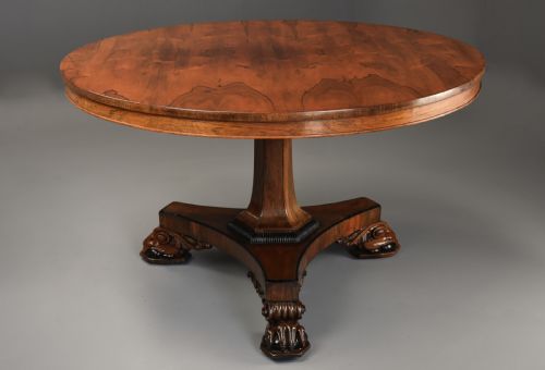 fig 1. A 19th-century William IV circular rosewood breakfast table featuring a figured veneer top on a faceted pedestal column and a triform plinth base with carved feet.