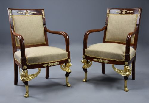 fig 2. A pair of late nineteenth-century French mahogany open armchairs featuring gilded winged lion front legs and neutral fabric upholstery.