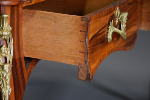 fig 4. A mid-19th-century French-style writing desk made from figured Goncalo Alves timber, featuring three drawers, gilt bronze Rococo mounts, cabriole legs, and a black leather inset top.