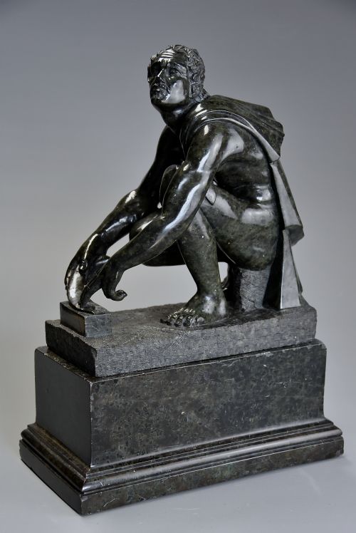 fig 2. A dark green carved marble sculpture of the classical crouching figure Arrotino mounted on a rectangular plinth.