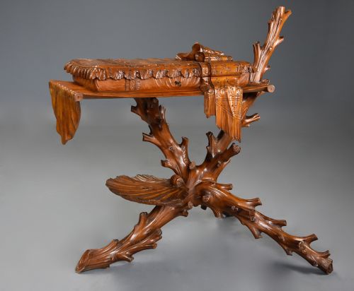 fig 1. A late nineteenth-century Italian carved pine grotto work table featuring tree-branch legs, a shell shelf, and a top detailed as a cushion with draped cloth.