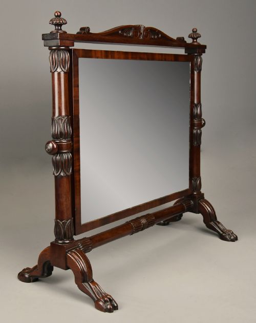 fig 3. A Regency Cuban mahogany dressing table mirror featuring a carved top cresting, reeded side columns with finials, and carved paw feet.