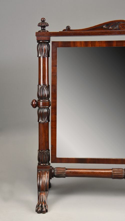 fig 4. A Regency Cuban mahogany dressing table mirror featuring a carved top cresting, reeded side columns with finials, and carved paw feet.