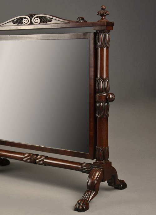 fig 5. A Regency Cuban mahogany dressing table mirror featuring a carved top cresting, reeded side columns with finials, and carved paw feet.