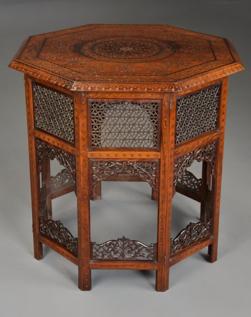 fig 1. A late nineteenth-century Anglo-Indian octagonal table crafted from dark wood with intricate floral bone inlay on top and carved fretwork panels along the base.