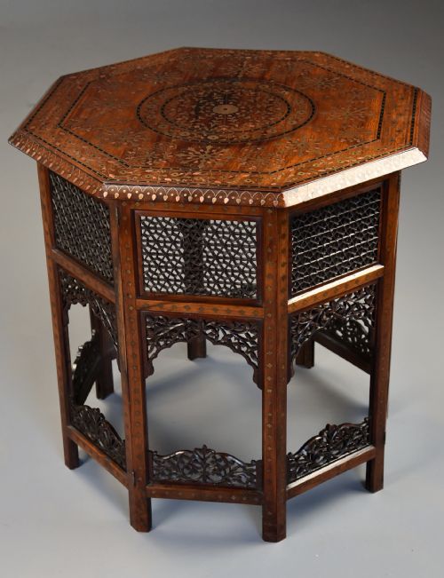 fig 2. A late nineteenth-century Anglo-Indian octagonal table crafted from dark wood with intricate floral bone inlay on top and carved fretwork panels along the base.
