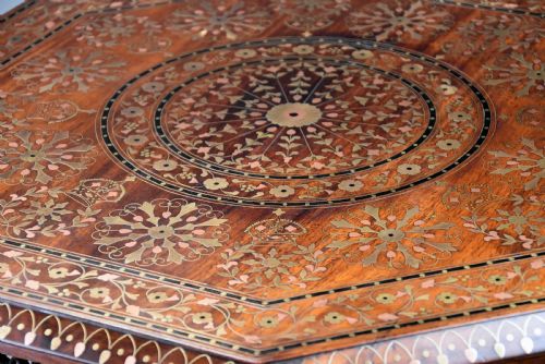 fig 3. A late nineteenth-century Anglo-Indian octagonal table crafted from dark wood with intricate floral bone inlay on top and carved fretwork panels along the base.