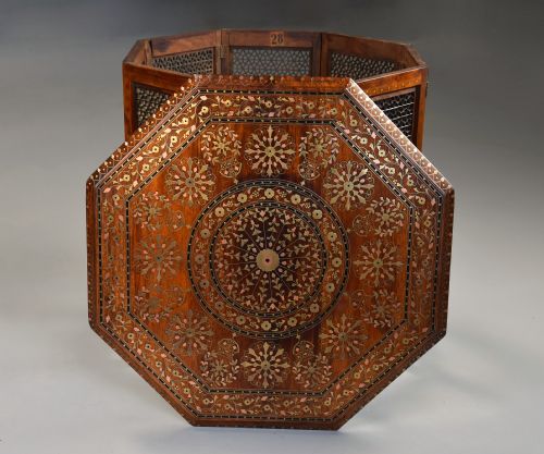 fig 4. A late nineteenth-century Anglo-Indian octagonal table crafted from dark wood with intricate floral bone inlay on top and carved fretwork panels along the base.
