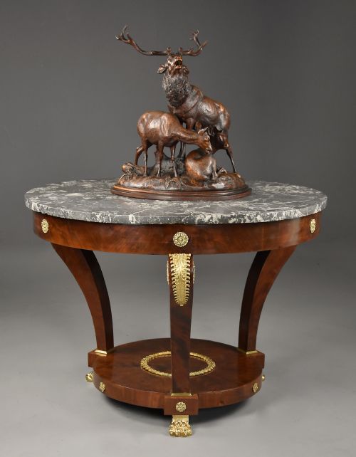 fig 1. A late 19th-century French Empire style circular gueridon table featuring a grey marble top, mahogany frame with gilded bronze mounts, and curved legs with paw feet.
