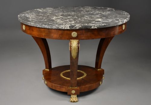 fig 2. A late 19th-century French Empire style circular gueridon table featuring a grey marble top, mahogany frame with gilded bronze mounts, and curved legs with paw feet.