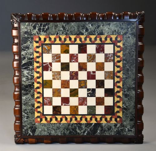 fig 3. A mid-19th century rosewood games table featuring a square specimen marble inlaid chessboard top resting on a carved pedestal stem and scroll feet.