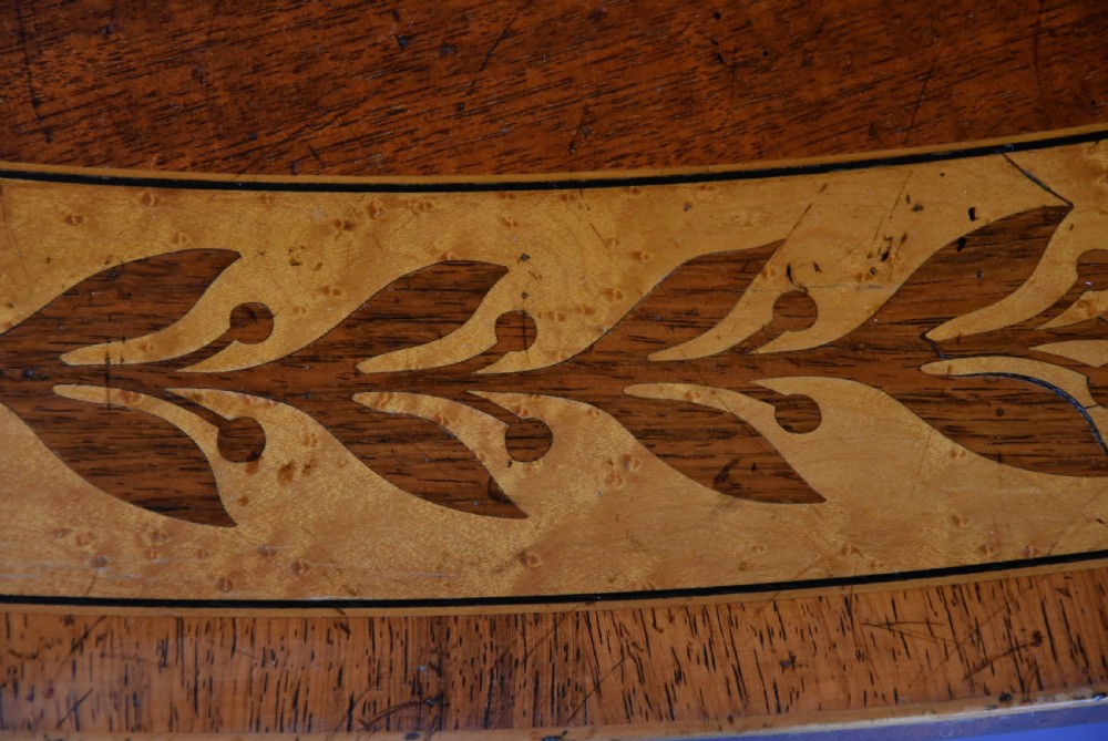 A large circular Regency style mahogany centre table featuring a crossbanded marquetry top and a tri-form base supported by three carved gilded dolphin figures with brass star details. View XII