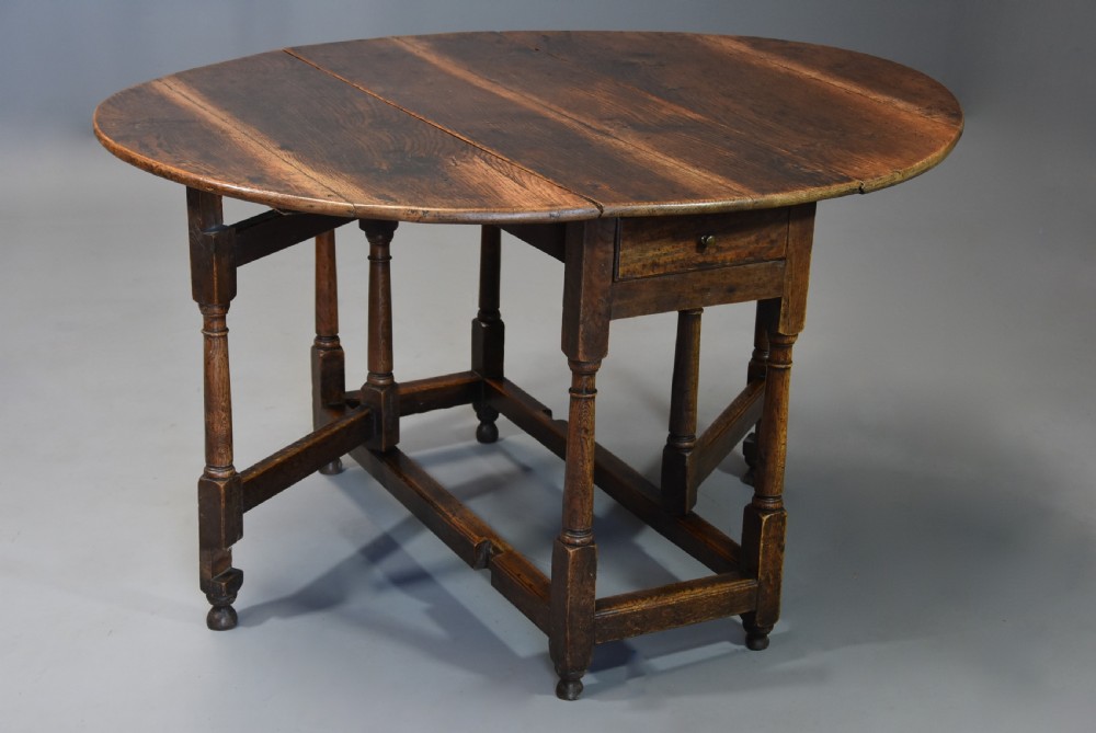 An early 18th century oak gateleg table with a rounded drop-leaf top, turned legs, and lower stretchers. View III